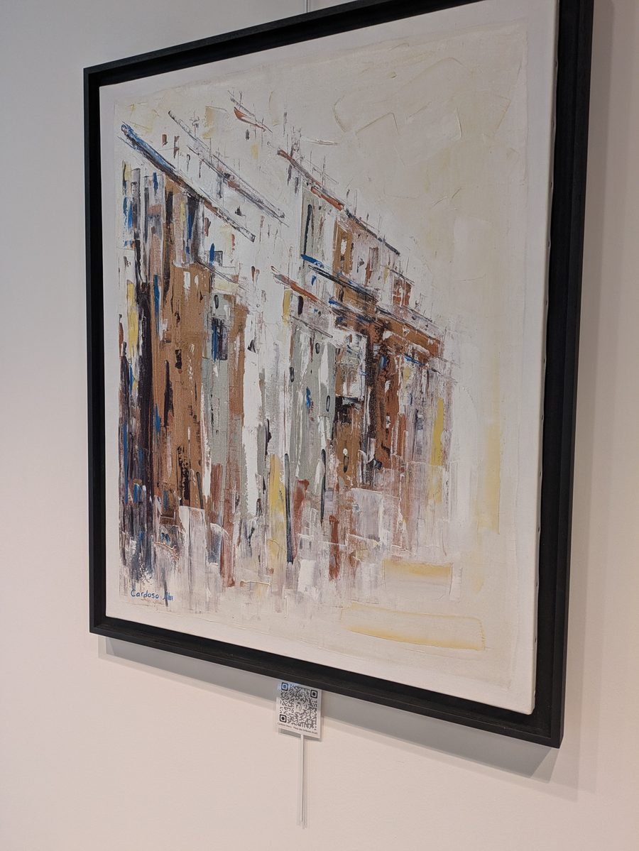 Toile de Manu Cardoso représentant une rue aux façades ocre et blanches, exposée à l’agence BARNES d’Aix-les-Bains